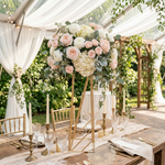 Load image into Gallery viewer, Decorative floral arrangement on a table with candles and glasses in an outdoor setting.
