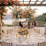 Load image into Gallery viewer, Outdoor wedding reception with floral centerpieces and table settings against a scenic backdrop.
