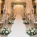Load image into Gallery viewer, Decorative wedding setup with floral arrangements and candles on a white carpet.
