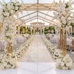 Load image into Gallery viewer, Decorative floral archway at a wedding reception with white flowers and clear tent.
