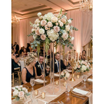Load image into Gallery viewer, Decorative floral arrangement on a table with guests in the background
