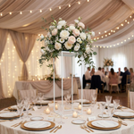 Load image into Gallery viewer, Decorative floral arrangement on a table with candles and plates in a softly lit room.
